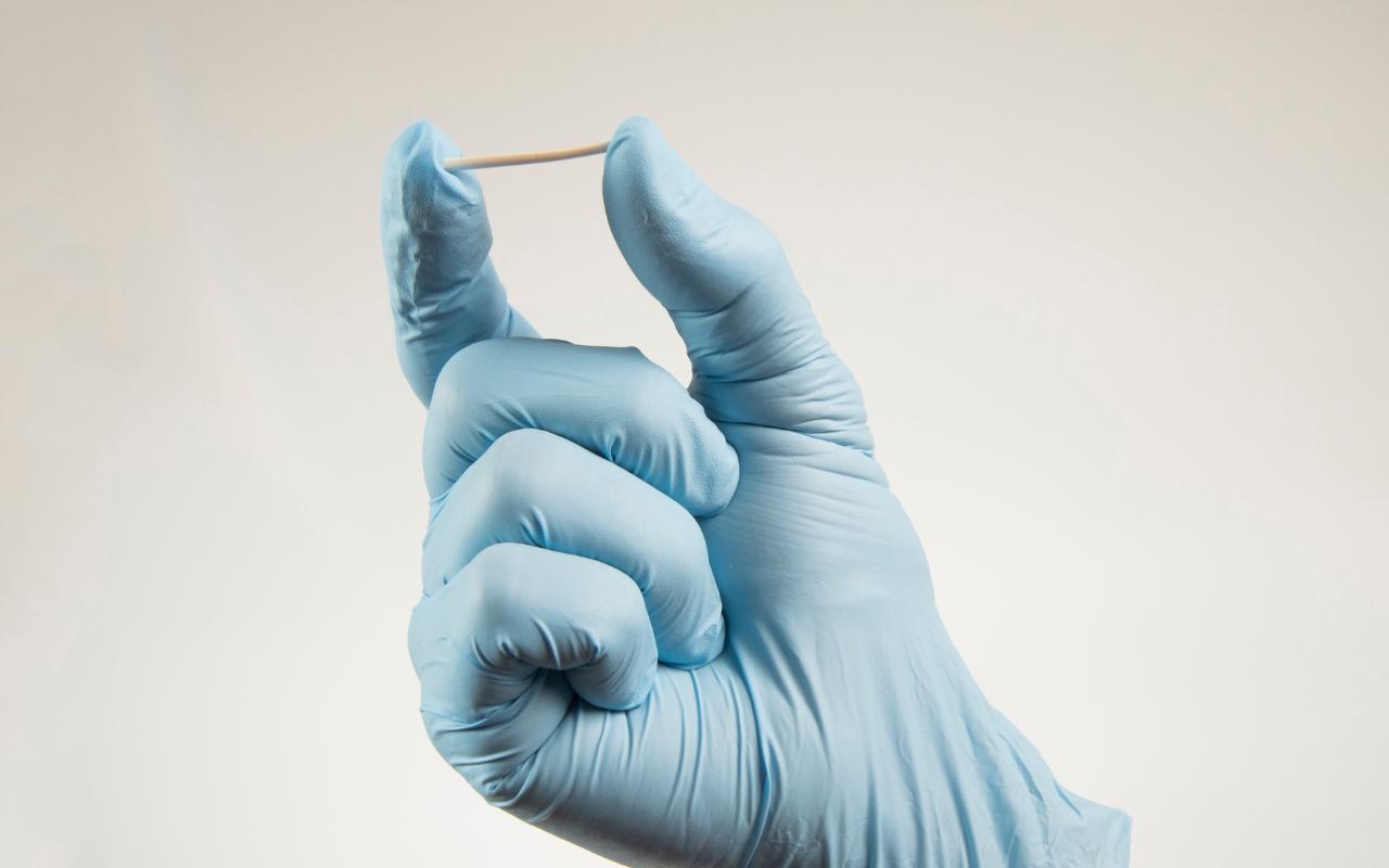 Médico usando luva e segurando Implanon.