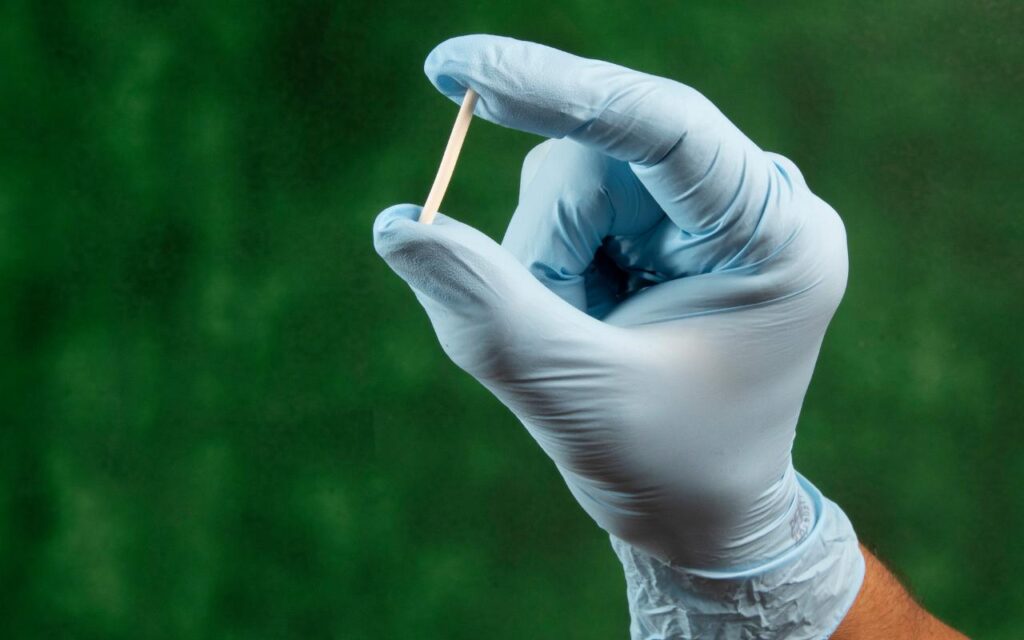 Médico usando luva azul e segurando Implanon.