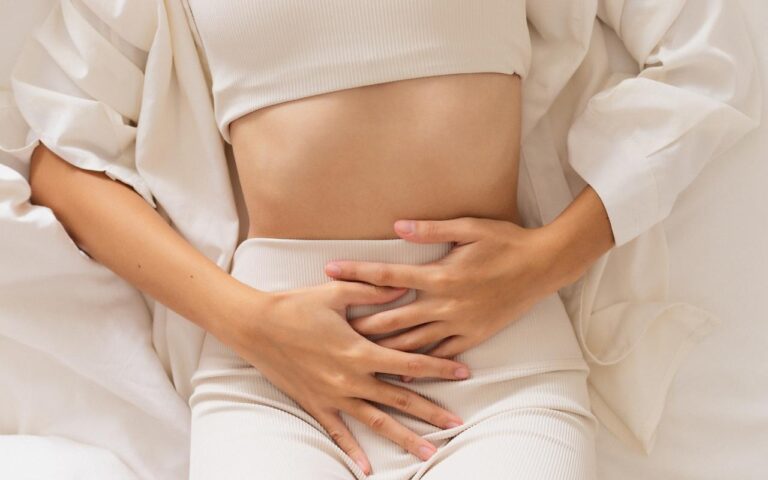 Mulher deitada na cama sentido dor por causa da endometriose.